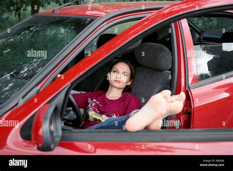 Young Woman Driver Resting In A Red Car Put Her Feet On The Car Window