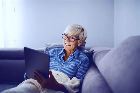 Attractive Caucasian Smiling Blonde Senior Woman Sitting On Sofa In