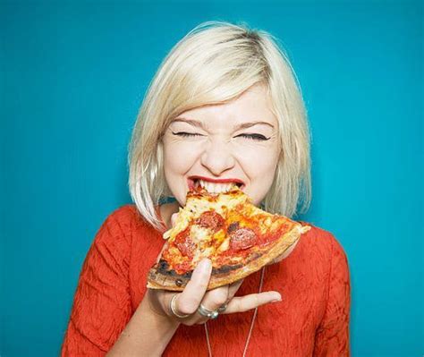 a woman biting into a slice of pizza