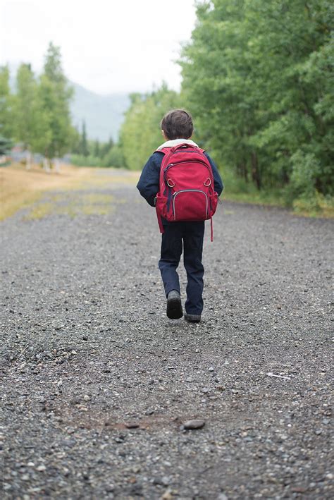 Young Boy Walks The Path To School Wearing A Backpack By Stocksy