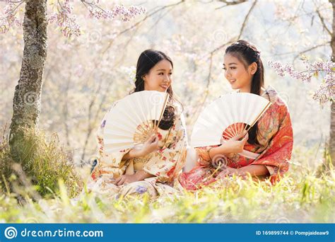 Two Japanese Girl Wearing A Kimono Holding A White Blow. Beautiful Female Wearing Traditional 