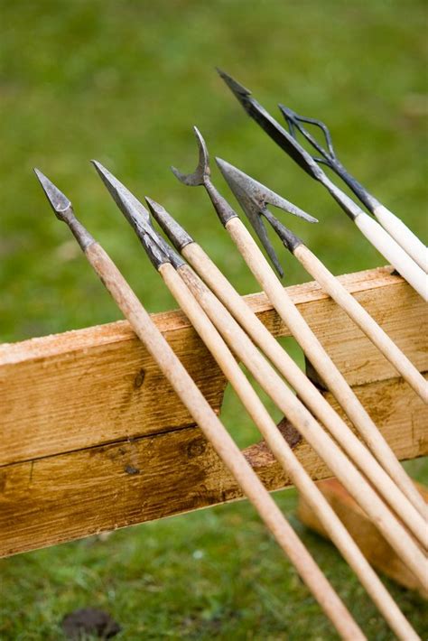 Several Arrows Are Lined Up On A Wooden Bench In Front Of Some Grass