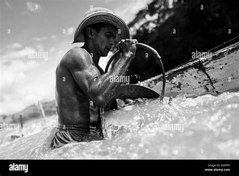 A Colombian Sand Miner Unloads A Bucket Full Of Gravel Into His Boat