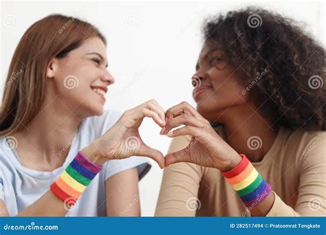 hand making a heart sign wearing lgbt rainbow flag wristband happy smiling homosexual lesbian