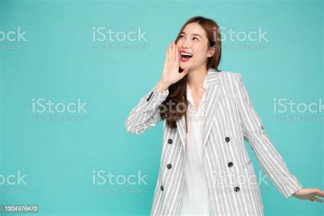 asian business woman with open mouths raising hands screaming announcement isolated on green