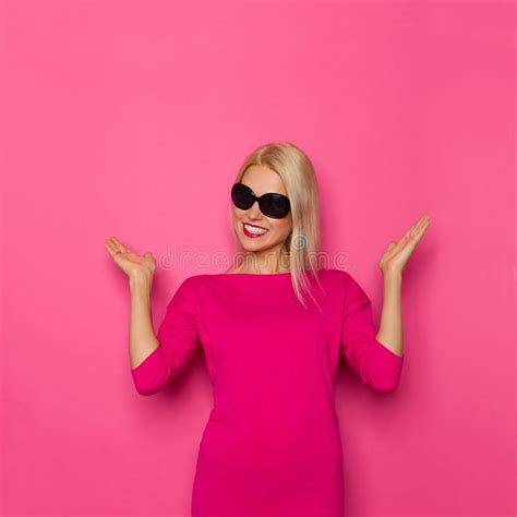 beautiful blond woman in pink sweater and sunglasses is presenting and smiling stock image
