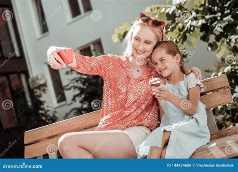 Mujer Positiva Encantada Que Toma Un Selfie Con Su Hija Foto De Archivo
