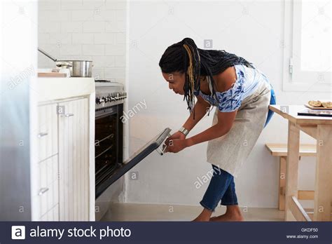 Woman Bending Down To Look Into The Oven In Her Kitchen Stock Photo Alamy