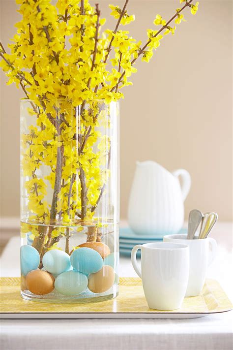 A Vase Filled With Yellow Flowers And Eggs On Top Of A Table Next To A Cup