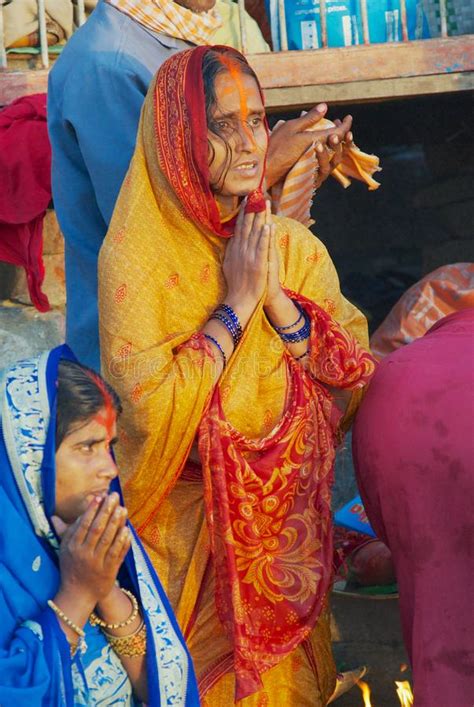 woman pilgrim prays at the bank of the holy ganges river at sunrise with other pilgrims at the