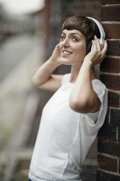Smiling Young Woman Listening Music With White Headphones Stock Photo