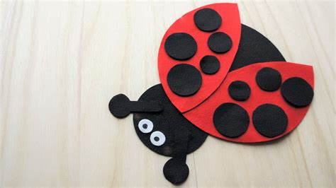 A Ladybug Made Out Of Felt Sitting On Top Of A Wooden Table