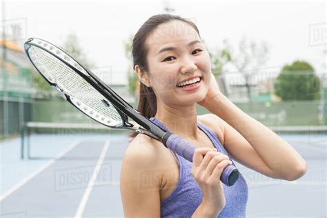 Portrait Of Young Female Tennis Player On Tennis Court Stock Photo