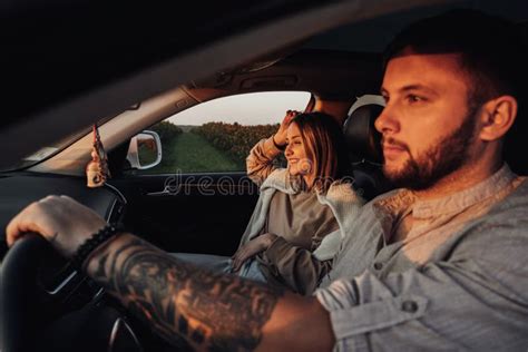 Tattooed Caucasian Man And Young Woman Sitting In The Car At Sunset
