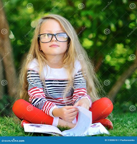 Portrait Of Sweet Little Girl Wearing Glasses Reading Book Sit Stock