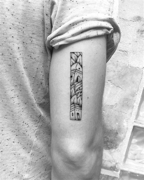 A Rectangular Tattoo Containing A Scenery Of Towers And Leaves Inked On