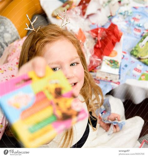 Girl With Long Reddish Blonde Hair Shows Her Christmas Present To The