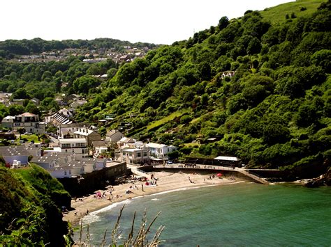 The Beach Is Surrounded By Lush Green Hills And Houses On Either Side