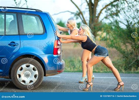 Two Beautiful Blonde Girls On High Heels Are Pushing Broken Car Stock