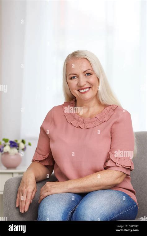 Portrait Of Beautiful Older Woman Sitting On Sofa Indoors Stock Photo