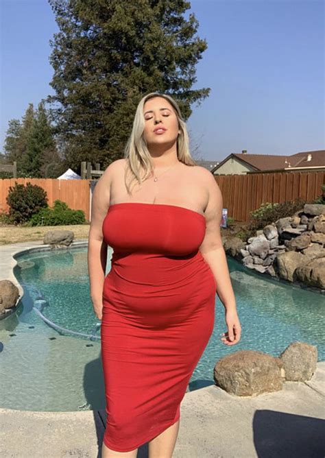 A Woman In A Red Dress Standing Next To A Pool
