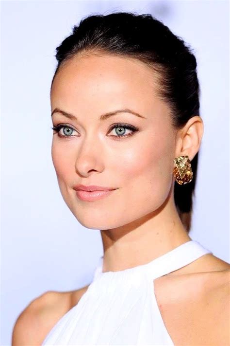 A Close Up Of A Person Wearing A White Dress And Gold Earring On Her