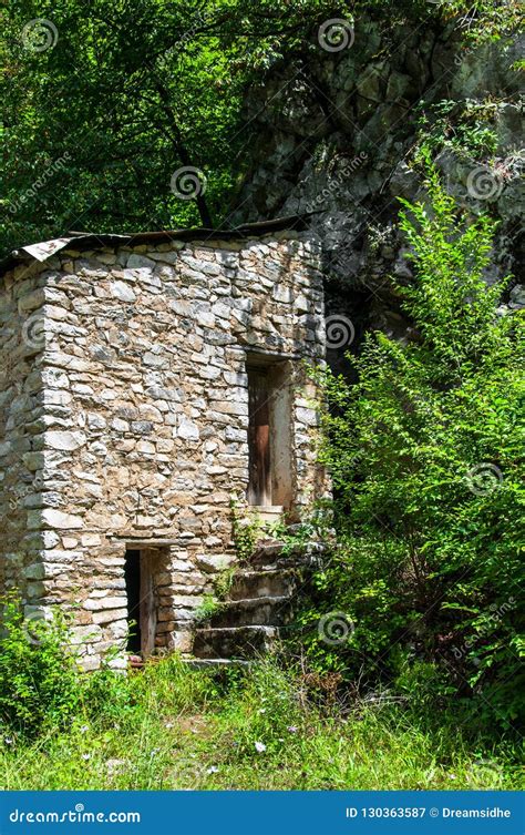 An Old Stone Building Standing By A Rock In The Middle Of A Fore Stock