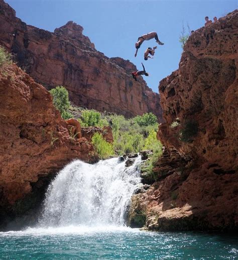 Two People Jumping Off The Side Of A Waterfall