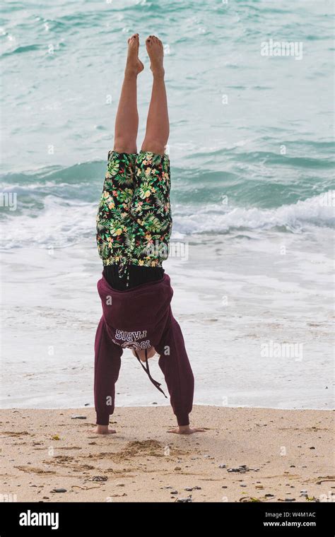 A Girl Performing A Handstand On The Beach At Fistral In Newquay In
