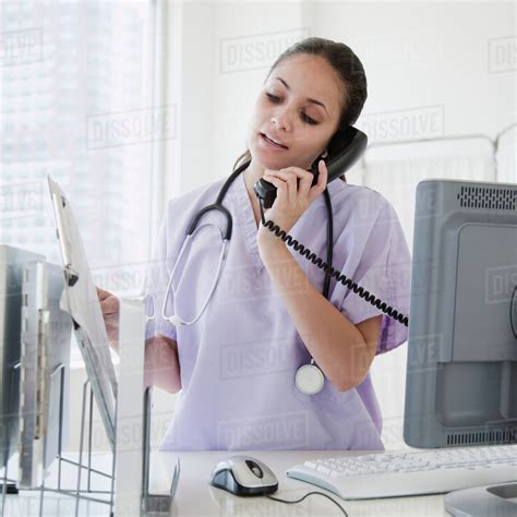 Mixed Race Nurse Talking On Telephone In Hospital Stock Photo Dissolve