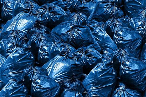 كومة من أكياس القمامة والنفايات البلاستيكية تحيط بسلة زرقاء في حالة من