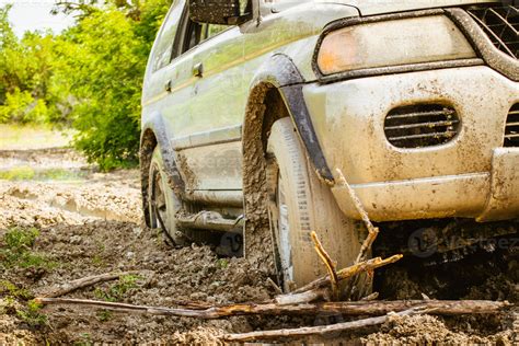 Close up view 4WD vehicle front wheel stuck in mud go backwards