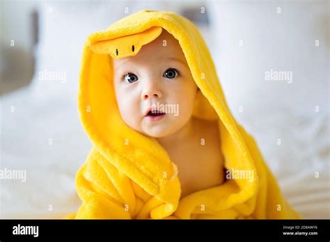 Baby Wearing Yellow Bathrobe Duck On Parents Bed After Bath Stock Photo