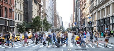 Busy Street Scene In New York City With Groups Of People Walking Across