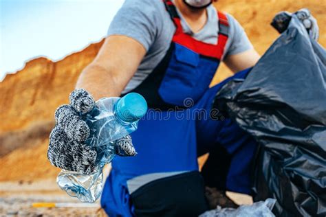 Hand Of A Man Volunteer Grabbing Plastic Litter Into A Waste Bag