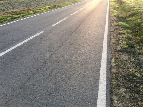 Sunlight Reflected Off Asphalt Straight Road Leading Into The Distance