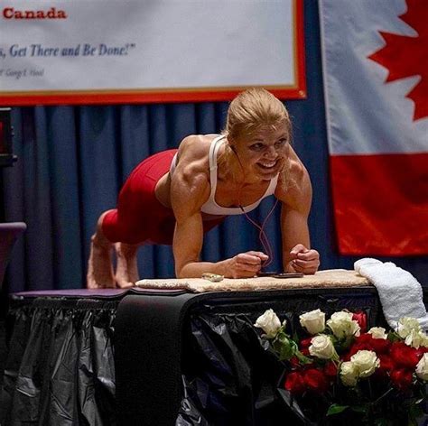 a woman is doing push ups on top of a table in front of a canadian flag