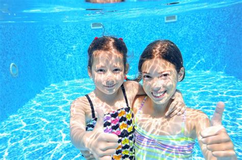 Дети плавают в бассейне под водой девушки имеют потеху в воде Стоковое