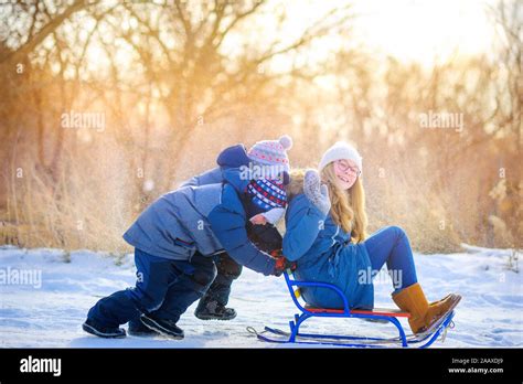 Happy Children Play In A Snowy Winter Park Sledding And Having Fun