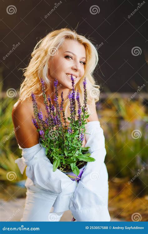 An Attractive Middle Aged Blonde Woman Topless In A White Shirt With Lavender Stock Photo