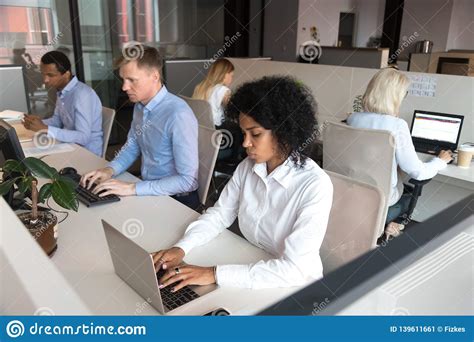 Diverse Millennial Employees Sitting At Desk Working In Coworking Space