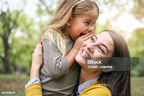 ibu dan anak di luar ruangan di padang rumput putri berbisik pada rahasia ibunya foto stok