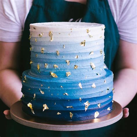 A Person Holding A Blue And White Cake With Gold Sprinkles On It