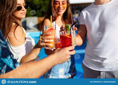 Close View Of Friends Having Fun At Poolside Summer Party Clinking