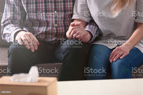 Closeup Of A Couple Holding Hands Together While Sitting On A Couch