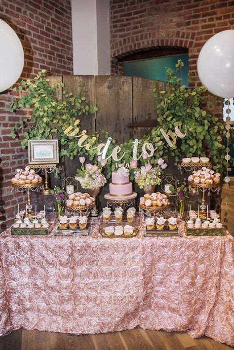 a table topped with cupcakes and cake next to balloons in front of a brick wall
