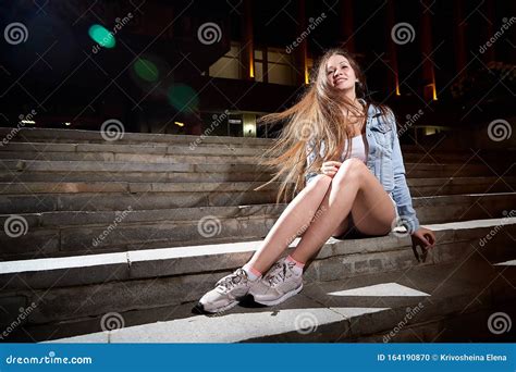 Young Beautiful Brunette Woman With Long Hair On The Steps Of Stairs On