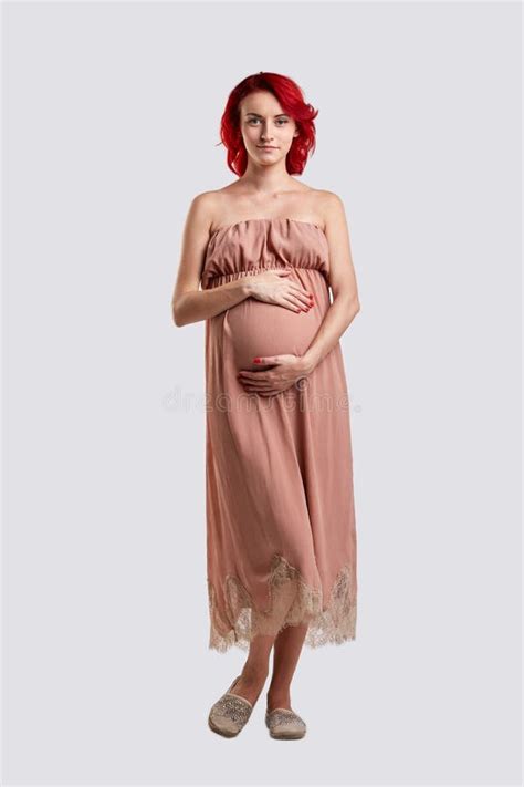 ein schwangeres mädchen in einem langen kleid umarmt ihren bauch weißer hintergrund stockbild
