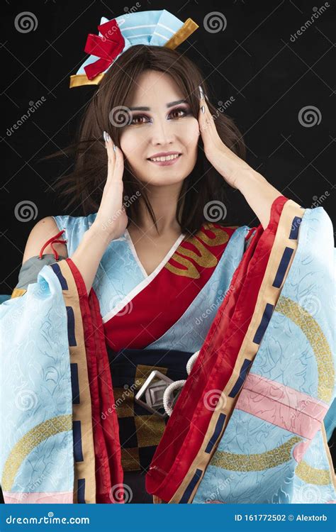 Beautiful Smiling Leggy Busty Cosplay Girl Wearing A Stylized Japanese Kimono Costume Cheerfully