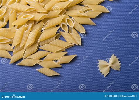 Tubular Penne And Single Farfalle Pasta On Blue Paper Stock Image